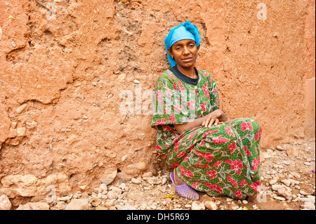 Frau mit blauem Tuch, Berber Frau, hocken auf dem Boden vor einer Schlamm-Mauer, südlichen Marokko, Marokko, Afrika Stockfoto