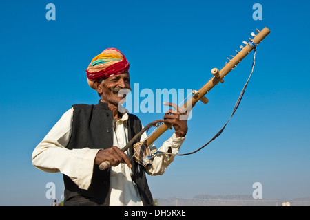 Ältere freundliche Inder, Rajasthani, einen bunten Turban tragen und spielen auf einer Sitar, Kamelmarkt Pushkar, Pushkar Stockfoto