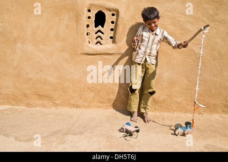 Junge spielt mit einem hausgemachten Spielzeugauto außerhalb ein Lehmhaus, Wüste Thar, Rajasthan, Indien Stockfoto