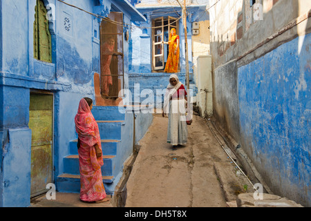 Vier Frauen in traditionellen Saris in einer Gasse mit blauen Häusern, Brahmpuri, Jodhpur, Rajasthan, Indien Stockfoto