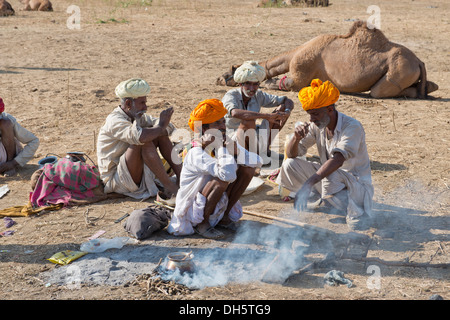 Vier ältere indische Männer mit Turbanen und tragen das traditionelle Dhoti Kleidungsstück auf dem Boden hocken, ist Essen zubereitet wird Stockfoto