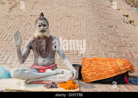 Sadhu, heiliger Mann oder Bummel durch asketische sitzen im Lotussitz auf ein Tuch, sein Körper ist mit weißer Asche im Zeichen beschmiert Stockfoto