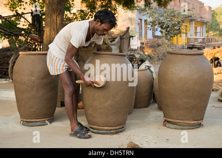 Inder bilden große Tontöpfe mit einem hölzernen Werkzeug, Khajuraho, Madhya Pradesh, Indien Stockfoto