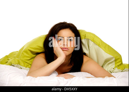 Schöne Brünette Frau im Bett unter einer grünen Decke müde und unglücklich gelegt Stockfoto