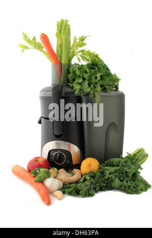 Entsafter, umgeben von gesunden Gemüse wie Karotten, Ingwer und Grünkohl, frischen Saft zu machen bereit Stockfoto