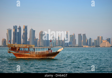 Tradition und moderne im Vergleich, Dhau, eine hölzerne Cargo Schiff im Abendlicht vor der Skyline von Doha Stockfoto