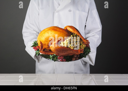 Nahaufnahme eines Kochs hält eine Platte mit einem Thanksgiving-Truthahn mit allem Drum und dran. Stockfoto