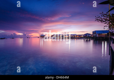 Sonnenuntergang über dem Meer auf der Insel Mabul, Borneo, Malaysia. Reflexionen des Dorfes Wasser in der Abenddämmerung Stockfoto