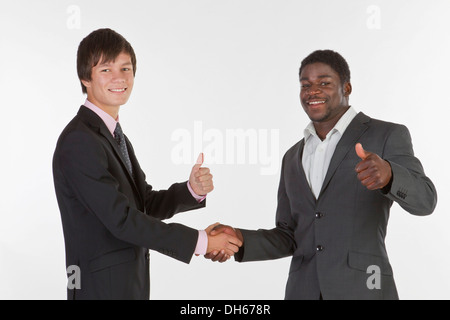 Zwei junge Männer aus verschiedenen Rassen Händeschütteln und ein Daumen-hoch-Geste Stockfoto