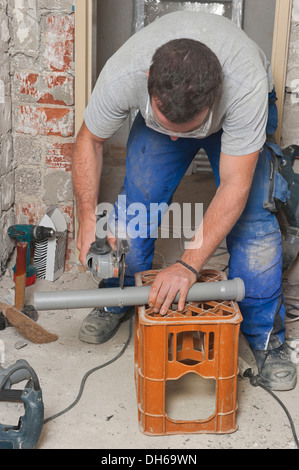 Ein Elektriker, Mechaniker für Sanitär, Heizung und Klimaanlage, Installation eines Kanalrohres Stockfoto