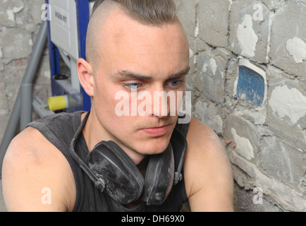 Ein junger Mann mit teilweise rasierten Kopf bei der Arbeit auf einer Baustelle, Sanierung, baden-wuerttemberg suchen Stockfoto