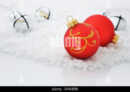 Rote Weihnachtskugel mit Schleife und Dekorationen auf Schnee Stockfoto