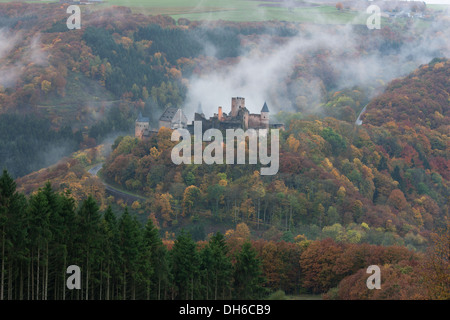 Burg Bourscheid mit Herbstfarben und Nebel, von der anderen Seite des Tales aus gesehen. Diekirch, Luxemburg. Stockfoto