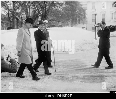 Ein historisches Foto zeigt den ehemaligen Präsidenten Harry S. Truman, der während seiner ersten Amtszeit über das schneebedeckte Gelände des Weißen Hauses spaziert. Stockfoto
