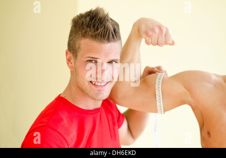 Jung, jungen Personaltrainer Client Bizeps mit Klebeband Meter messen Stockfoto