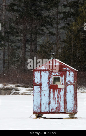Eine zerschlagene rote und blaue Eis Angeln Hütte in einem Schneesturm. Stockfoto