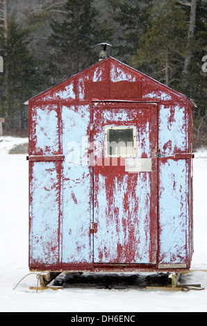 Eine zerschlagene rote und blaue Eis Angeln Hütte in einem Schneesturm. Stockfoto