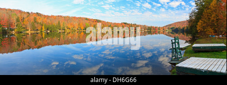 Ein Rettungsschwimmer Stuhl sitzt auf dem Rand der Barsch See in den Catskill Mountains mit einem reflektierten Himmel im Herbst in New York Stockfoto