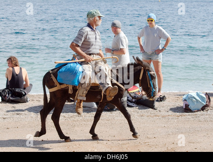 Mister auf einem Esel reitet vorbei zum Strand. die Insel Symi, Griechenland Stockfoto