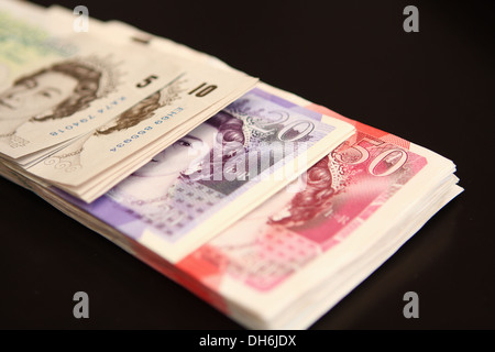Ein Bündel von Sterling £50, £20, £10 und £5 Noten vor schwarzem Hintergrund Stockfoto