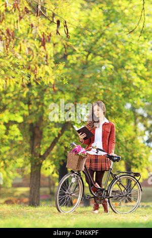 Junge Frau mit einem Buch in einem Park Fahrrad Stockfoto