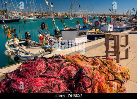 Fischerboote und bunte Netze entlang des Kais im Hafen von Marina di Ragusa. Stockfoto