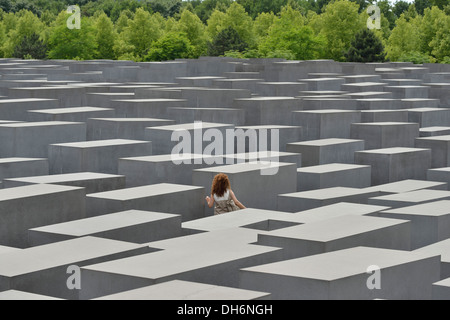 Berlin. Deutschland. Denkmal für die ermordeten Juden Europas / Holocaust-Mahnmal, eine einsame Frau wandert zwischen den Stelen. Stockfoto