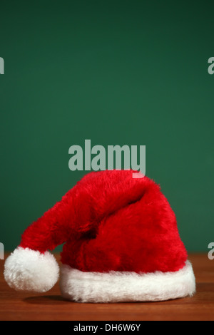 Weihnachtsmann rot Hut mit textfreiraum auf grün und Holz Hintergrund Stockfoto