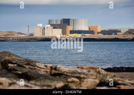 Wylfa Nuclear Power Station gesehen von Cemlyn Bay mit Felsen im Vordergrund Anglesey North Wales UK Stockfoto