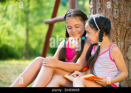 Porträt von zwei glücklichen hispanische Schwestern lesen im park Stockfoto