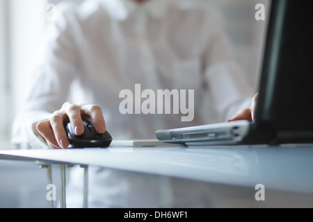 Zarte Frauenhand mit schnurlosen Maus auf Glastisch Stockfoto