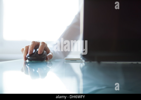 Zarte Frauenhand mit schnurlosen Maus auf Glastisch Stockfoto