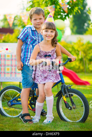 Zwei glückliche Kinder in Liebe sitzen auf dem Fahrrad Stockfoto