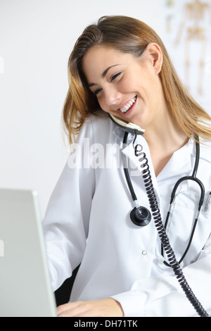 Schöne Arzt in einem Gespräch am Telefon sprechen und Surfen in einem laptop Stockfoto