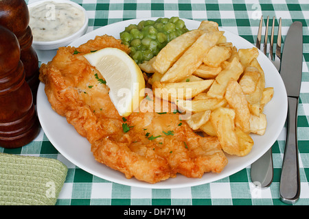 Teller mit Fish And Chips mit Erbsenpüree und einer Scheibe Zitrone auf einem Diner Tisch. Ein traditionelles Gericht der britischen Küste Stockfoto