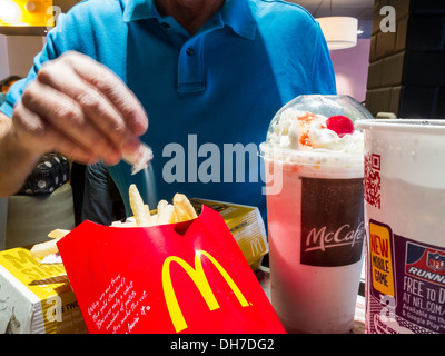 Menschen Essen bei McDonald's Restaurant, Telefon, Pommes Frites und Milkshake Mahlzeit, NYC, USA Stockfoto