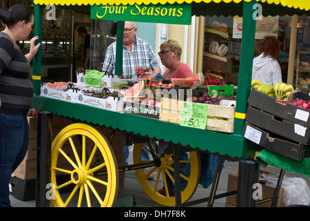 Obst-Verkäufer Verkauf von Produkten aus reich verzierten grün und gelb gestalteten mobilen stall Stockfoto