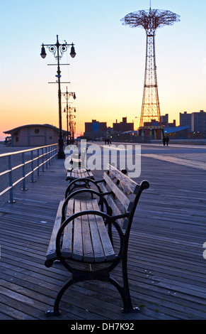 Bänke auf der Promenade von Coney Island in der Dämmerung mit dem Fallschirm fallen im Hintergrund Stockfoto