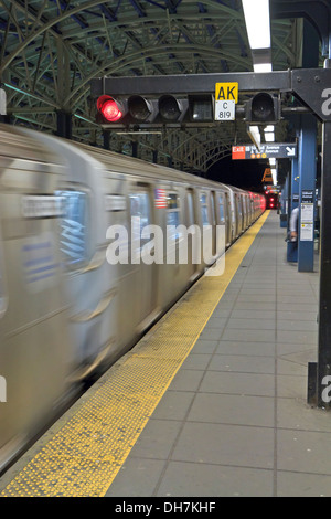 Eine u-Bahn Zug in Bewegung, wie kommt es an Stillwell Avenue Station in der Nacht in Coney Island, Brooklyn Stockfoto