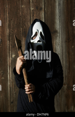 Mann in beängstigend "Schrei" Maske hält Axt. Maske der Sensenmann. Weißen Geistermaske Karneval und schwarze Kapuze. Scary Movie Film. Stockfoto