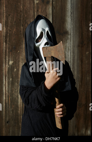 Mann in beängstigend "Schrei" Maske hält Axt. Maske der Sensenmann. Weißen Geistermaske Karneval und schwarze Kapuze. Scary Movie Film. Stockfoto