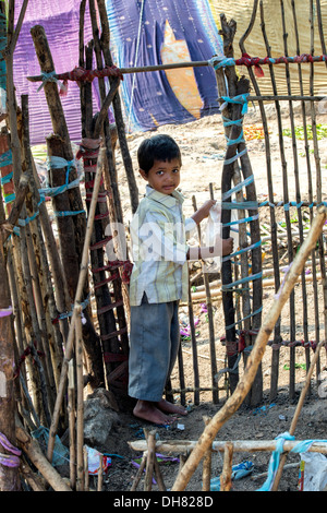 Niedrigere Kaste Indianerjunge stehend in einem Ziegenstall vor seinem Bender / Zelt / shelter.  Andhra Pradesh, Indien Stockfoto