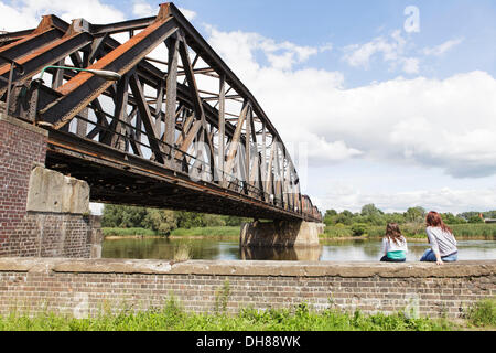 Eisenbahn-Brücke über den Grenzfluss Oder, deutsch-polnischen Grenze, Kuestrin, Kostrzyn, zwei Mädchen sitzen auf dem Kai Wand zugewandten Stockfoto