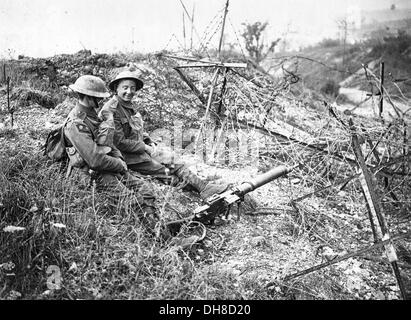 Ersten Weltkrieg Stellungskrieg. Britische Soldaten sitzen auf einer erbeuteten deutschen Position unter Stacheldraht Verwicklungen und verworfen Pistole Stockfoto