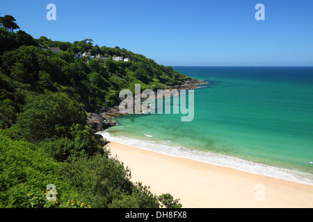 Ein goldener Sandstrand mit türkisblauem Meer und üppigen grünen Klippen. Stockfoto