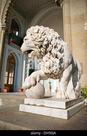 Skulptur eines Löwen mit einem Ball auf einem Hintergrund von Palast Stockfoto