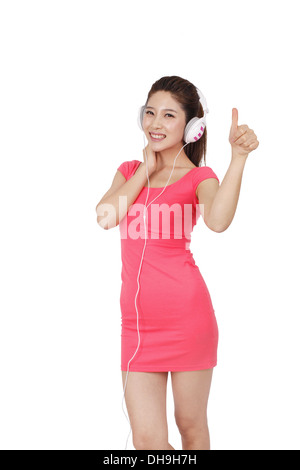 Junge Frau in rosa Kleid mit Kopfhörer Stockfoto