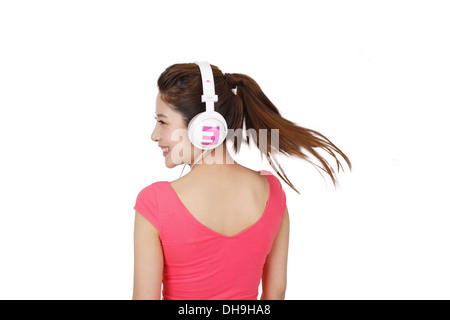 Junge Frau in rosa Kleid mit Kopfhörer Stockfoto