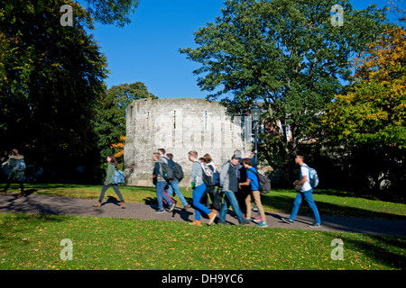 Studenten Jugendliche gehen im Herbst am Multangular Tower vorbei Museum Gardens York North Yorkshire England Vereinigtes Königreich Großbritannien Stockfoto