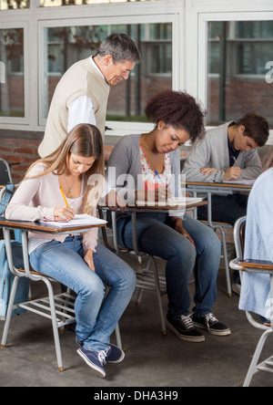 Studenten, die Prüfung zu schreiben, während Professor In Classr Aufsicht Stockfoto